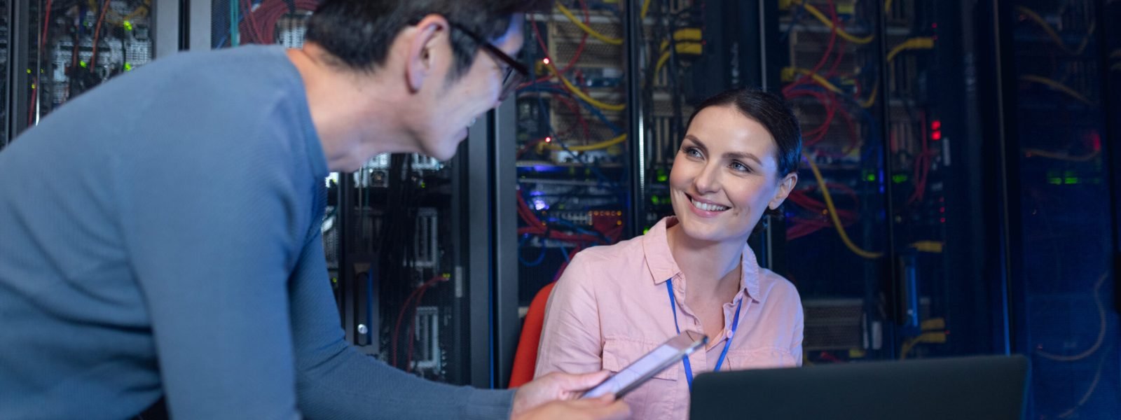 Diverse male and female engineers discussing over a digital tablet in computer server room. database server management and maintenance concept